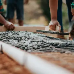 Praca z betonem na budowie, wygładzanie powierzchni kielnią.