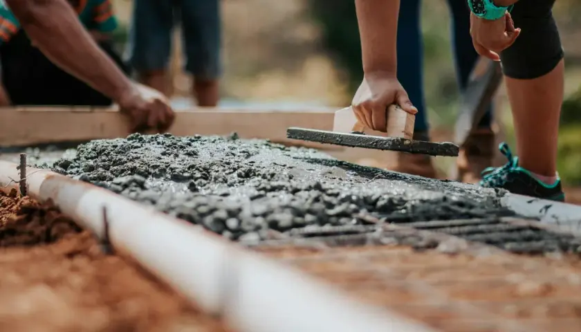 Praca z betonem na budowie, wygładzanie powierzchni kielnią.